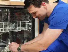 Dishwasher repair technician inspecting and servicing an open dishwasher in New Haven, CT