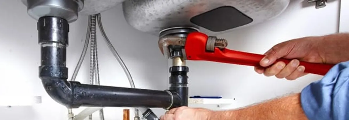Garbage disposal repair technician tightening the sink drain and disposal connection in New Haven, CT