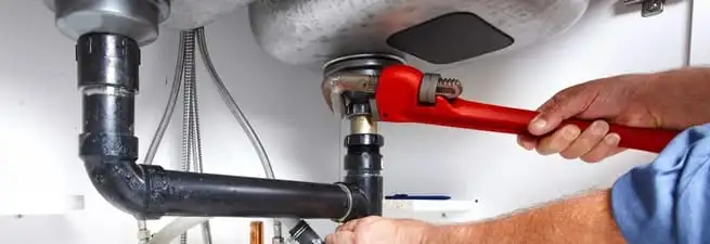 Garbage disposal repair technician tightening the sink drain and disposal connection in New Haven, CT