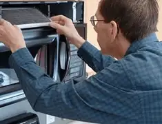 Appliance repair technician replacing a microwave vent filter in New Haven, CT