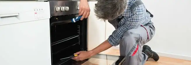 Oven repair technician inspecting and servicing an electric oven in New Haven, CT