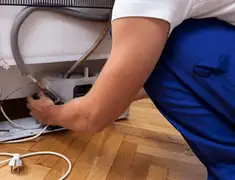 Appliance repair technician fixing refrigerator water line and connections in New Haven, CT