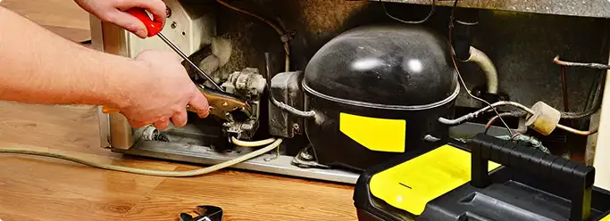 Refrigerator repair technician fixing the compressor and wiring in New Haven, CT