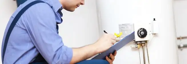 Water heater repair technician inspecting the unit and recording service notes in New Haven, CT
