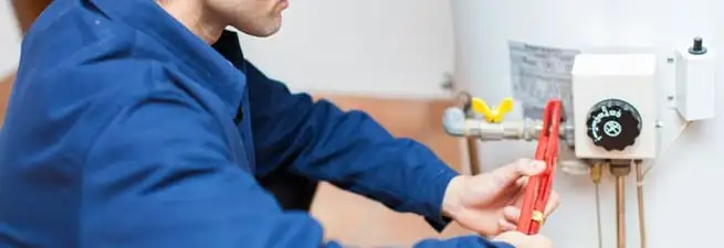 Water heater repair technician adjusting the temperature control and gas valve in New Haven, CT